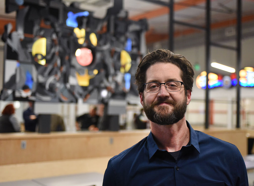 Local artist David Spear poses for a portrait in front of his work after a dedication ceremony for the new Columbia Sports Fieldhouse